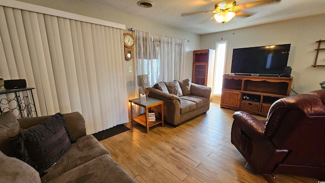 living room with light hardwood / wood-style floors, a textured ceiling, and ceiling fan