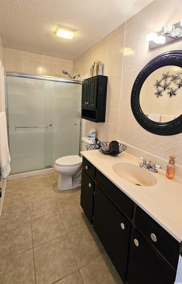 bathroom featuring a textured ceiling, an enclosed shower, toilet, tile walls, and vanity