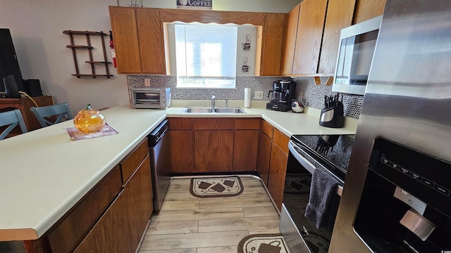 kitchen with backsplash, stainless steel appliances, sink, and light wood-type flooring