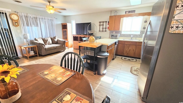 kitchen featuring tasteful backsplash, sink, light hardwood / wood-style floors, stainless steel appliances, and ceiling fan