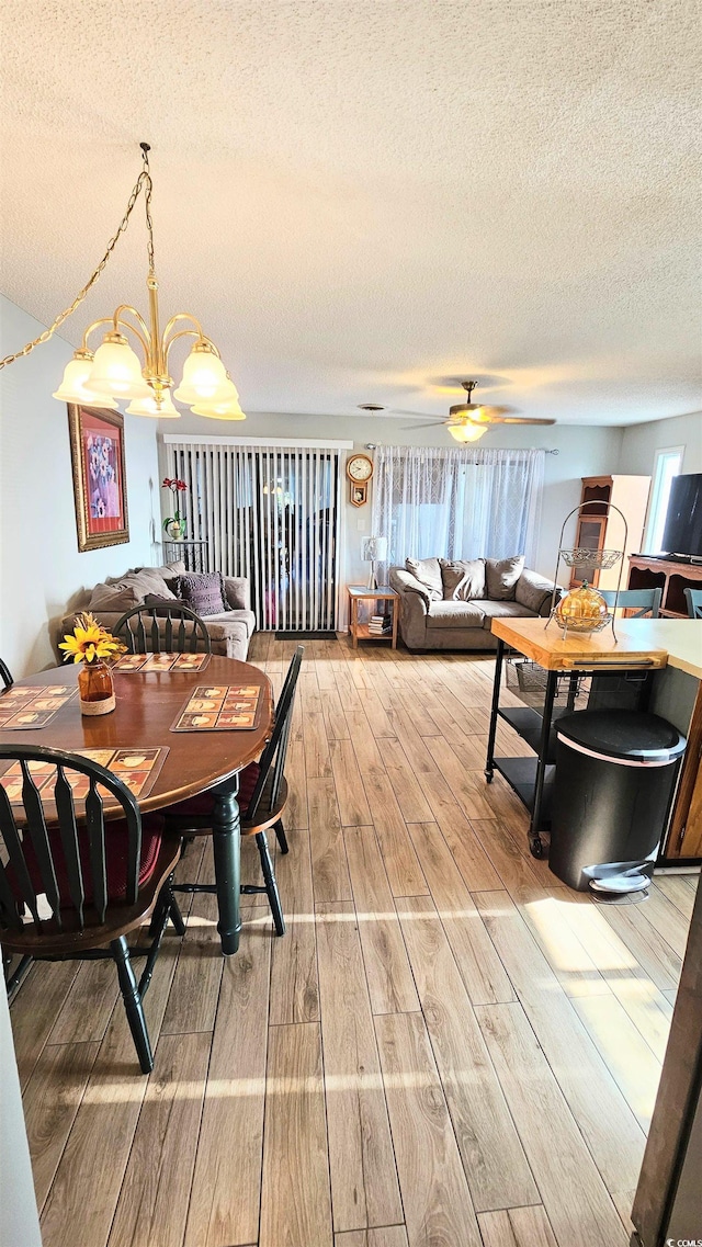 dining room with hardwood / wood-style flooring, a textured ceiling, and ceiling fan with notable chandelier