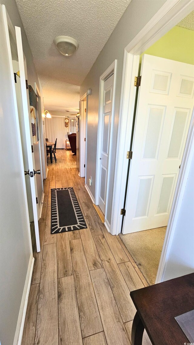 hallway with a textured ceiling and light wood-type flooring