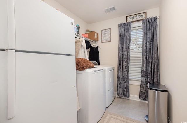 laundry area with washing machine and dryer and light tile patterned floors