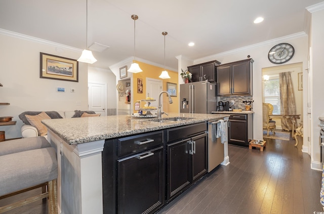 kitchen with ornamental molding, an island with sink, stainless steel appliances, and dark hardwood / wood-style floors