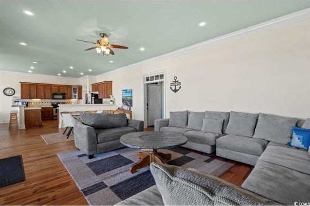 living room with dark wood-type flooring, crown molding, and ceiling fan