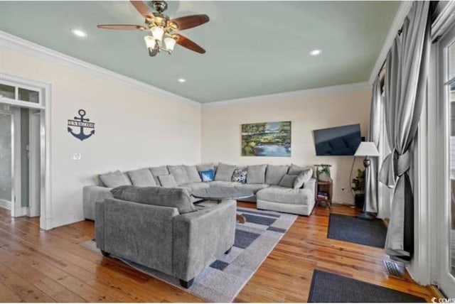 living room with ornamental molding, wood-type flooring, and ceiling fan