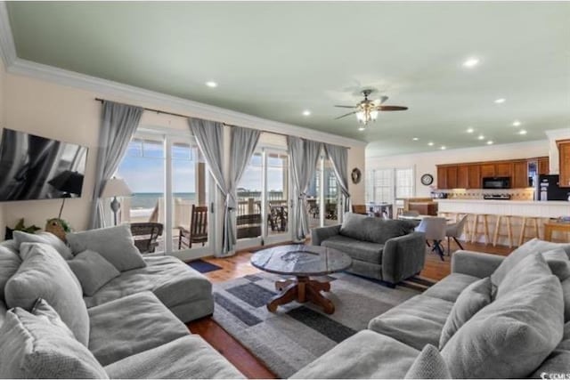 living room with crown molding, hardwood / wood-style flooring, a water view, and ceiling fan