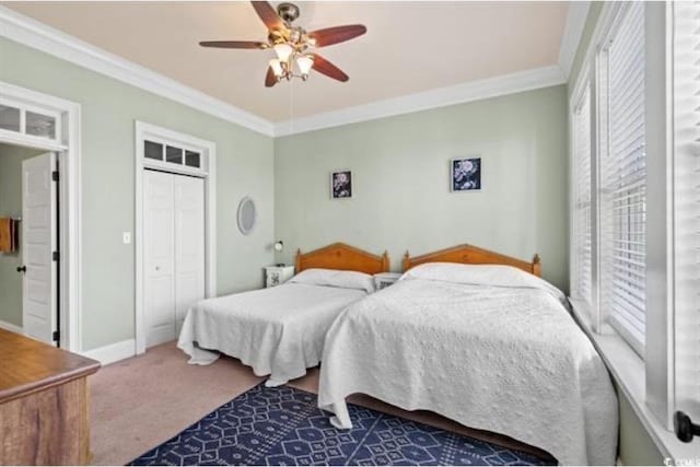 carpeted bedroom with a closet, ceiling fan, and crown molding