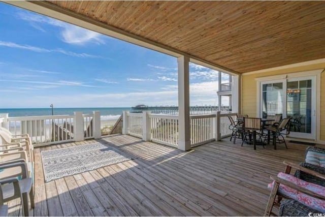 wooden terrace featuring a water view and a view of the beach