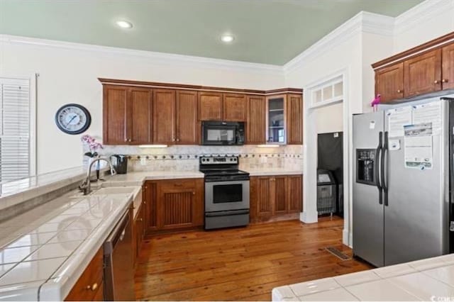 kitchen featuring appliances with stainless steel finishes, sink, tile countertops, dark wood-type flooring, and decorative backsplash