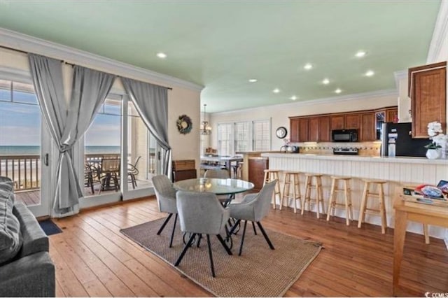 dining area featuring a water view, crown molding, and hardwood / wood-style flooring