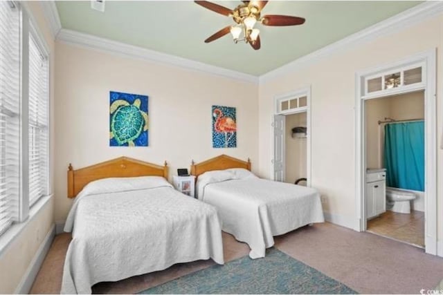 carpeted bedroom featuring ceiling fan, ornamental molding, and ensuite bath