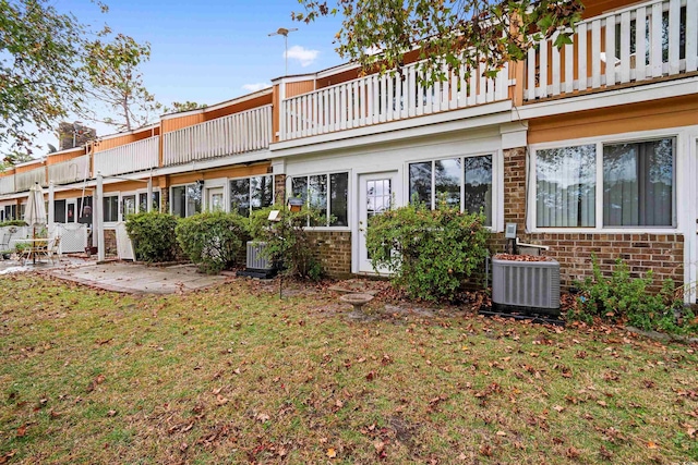 rear view of house with a yard, a balcony, a patio area, and central AC