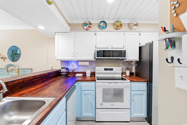 kitchen with appliances with stainless steel finishes, white cabinetry, tasteful backsplash, and wood counters