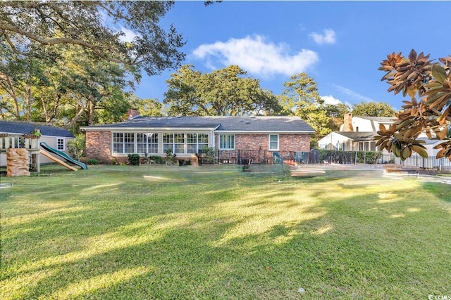 back of property with a playground and a lawn