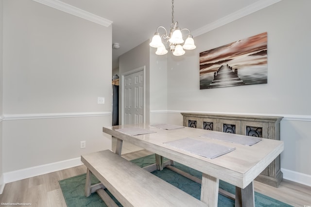 dining area with crown molding, a notable chandelier, and light wood-type flooring