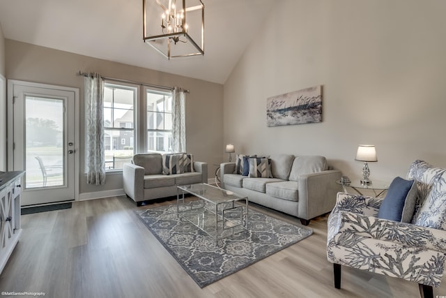 living room featuring high vaulted ceiling, a notable chandelier, and light wood-type flooring