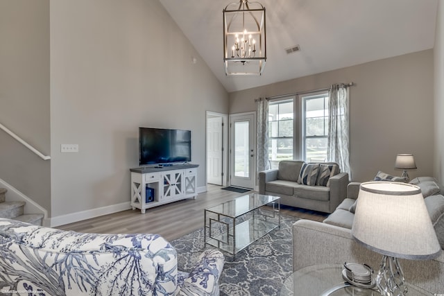 living room with hardwood / wood-style floors, a chandelier, and high vaulted ceiling