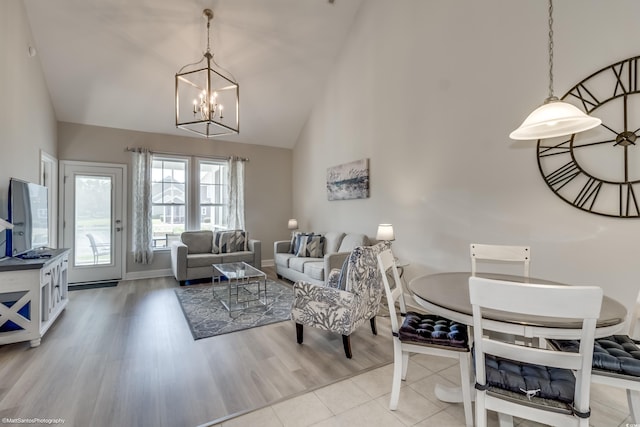 living room with light hardwood / wood-style flooring, high vaulted ceiling, and a notable chandelier