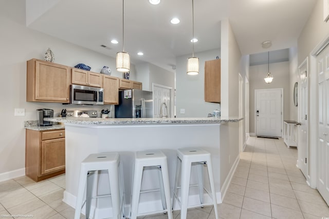 kitchen featuring appliances with stainless steel finishes, decorative light fixtures, and a kitchen bar