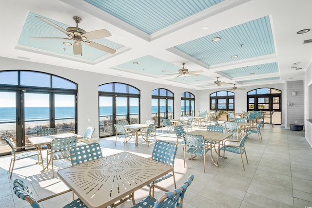 sunroom featuring a water view, ceiling fan, coffered ceiling, and beamed ceiling