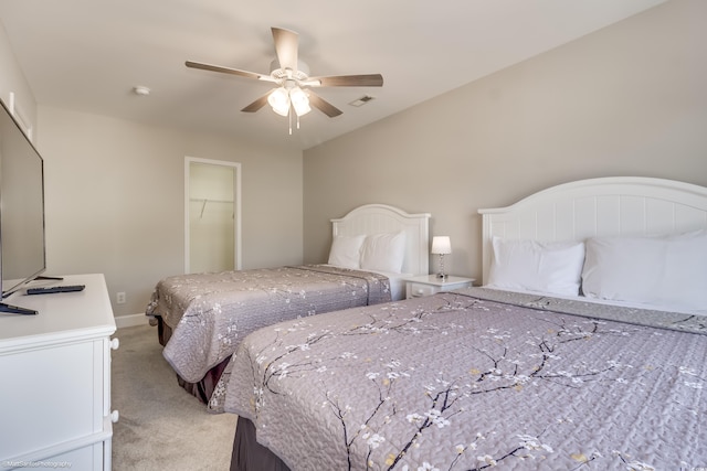 bedroom with a spacious closet, light carpet, a closet, and ceiling fan