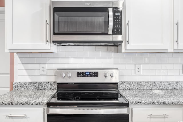 kitchen with white cabinetry, stainless steel appliances, and light stone countertops