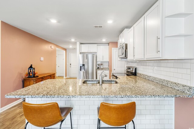 kitchen featuring white cabinetry, kitchen peninsula, and stainless steel appliances