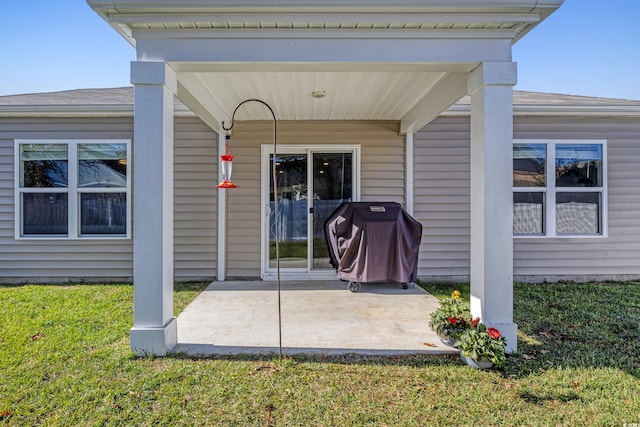 entrance to property featuring a patio and a lawn