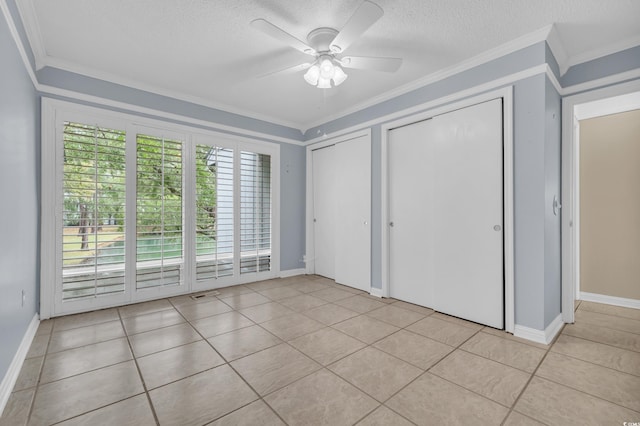 unfurnished bedroom featuring a textured ceiling, two closets, ceiling fan, crown molding, and light tile patterned floors