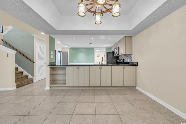 kitchen with tasteful backsplash, cream cabinets, light tile patterned floors, and appliances with stainless steel finishes