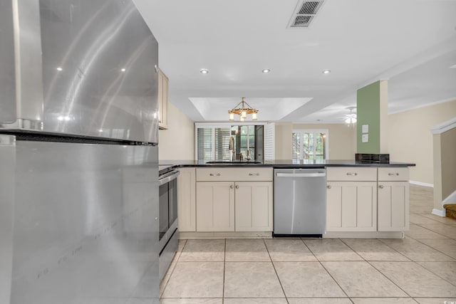 kitchen featuring appliances with stainless steel finishes, a raised ceiling, sink, light tile patterned floors, and white cabinetry