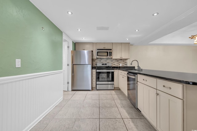 kitchen with cream cabinets, sink, decorative backsplash, light tile patterned floors, and stainless steel appliances