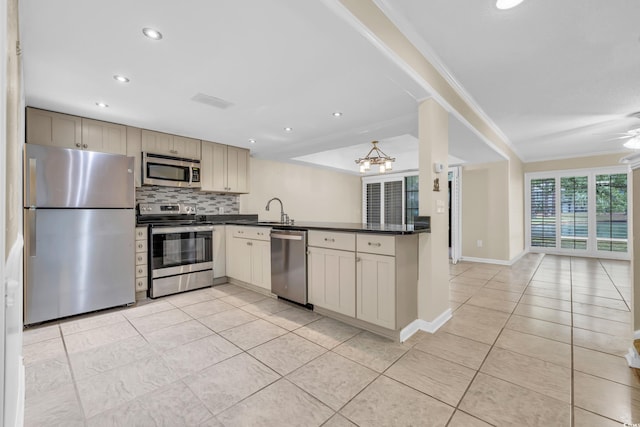 kitchen featuring stainless steel appliances, backsplash, kitchen peninsula, cream cabinets, and ornamental molding