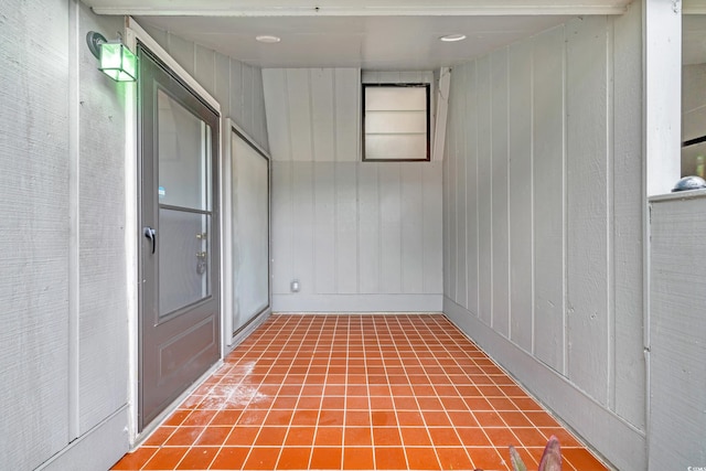 interior space with tile patterned floors and wood walls