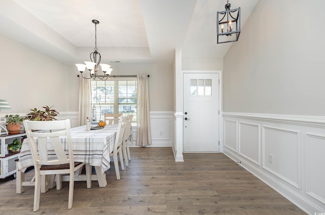 dining space featuring dark wood-type flooring, a tray ceiling, and a chandelier