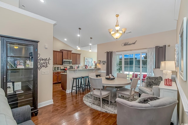 dining area with dark hardwood / wood-style flooring, a notable chandelier, crown molding, and vaulted ceiling