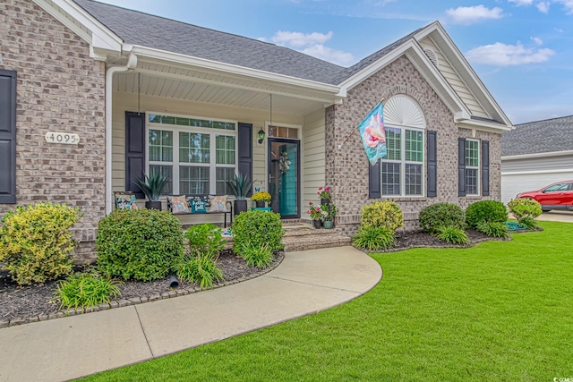 view of exterior entry with a garage, a yard, and covered porch