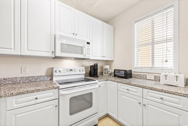 kitchen with white appliances, light stone counters, a healthy amount of sunlight, and white cabinets