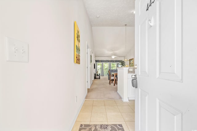 corridor featuring a textured ceiling and light tile patterned floors