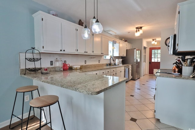 kitchen with stainless steel appliances, kitchen peninsula, white cabinets, and pendant lighting