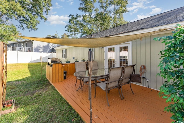 deck featuring french doors, grilling area, and a lawn