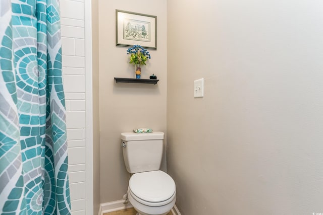 bathroom featuring toilet and curtained shower