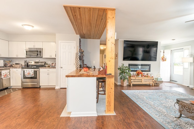 kitchen featuring butcher block counters, a kitchen breakfast bar, stainless steel appliances, white cabinetry, and dark hardwood / wood-style flooring