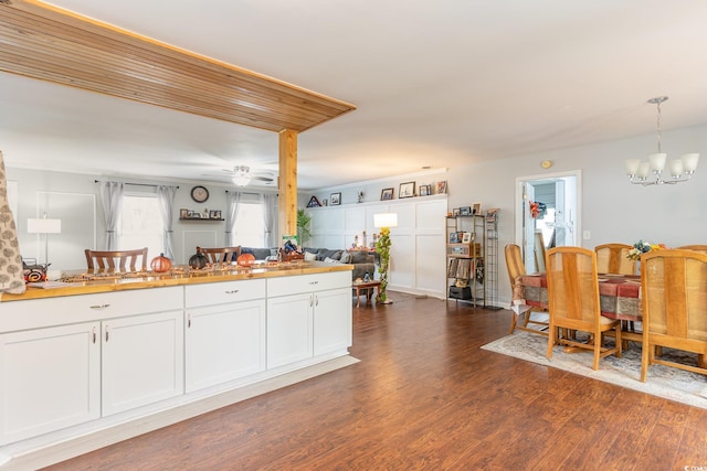 kitchen with white cabinetry, dark wood-type flooring, ceiling fan with notable chandelier, and pendant lighting