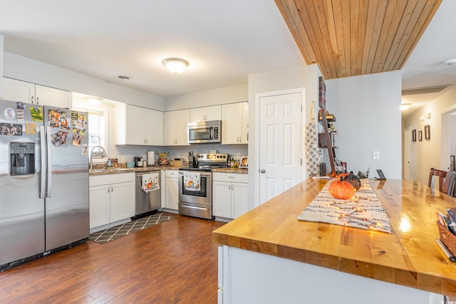 kitchen with butcher block countertops, white cabinetry, and stainless steel appliances