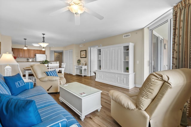 living room featuring visible vents, baseboards, wood finished floors, and ceiling fan