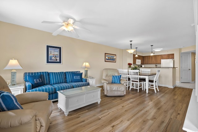 living room with light wood-style flooring, baseboards, and ceiling fan