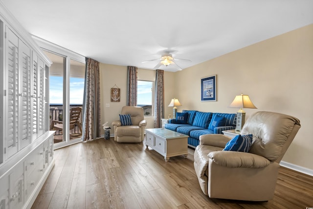 living area with baseboards, a ceiling fan, and wood finished floors