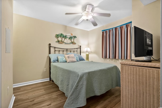 bedroom featuring wood finished floors, baseboards, and a ceiling fan
